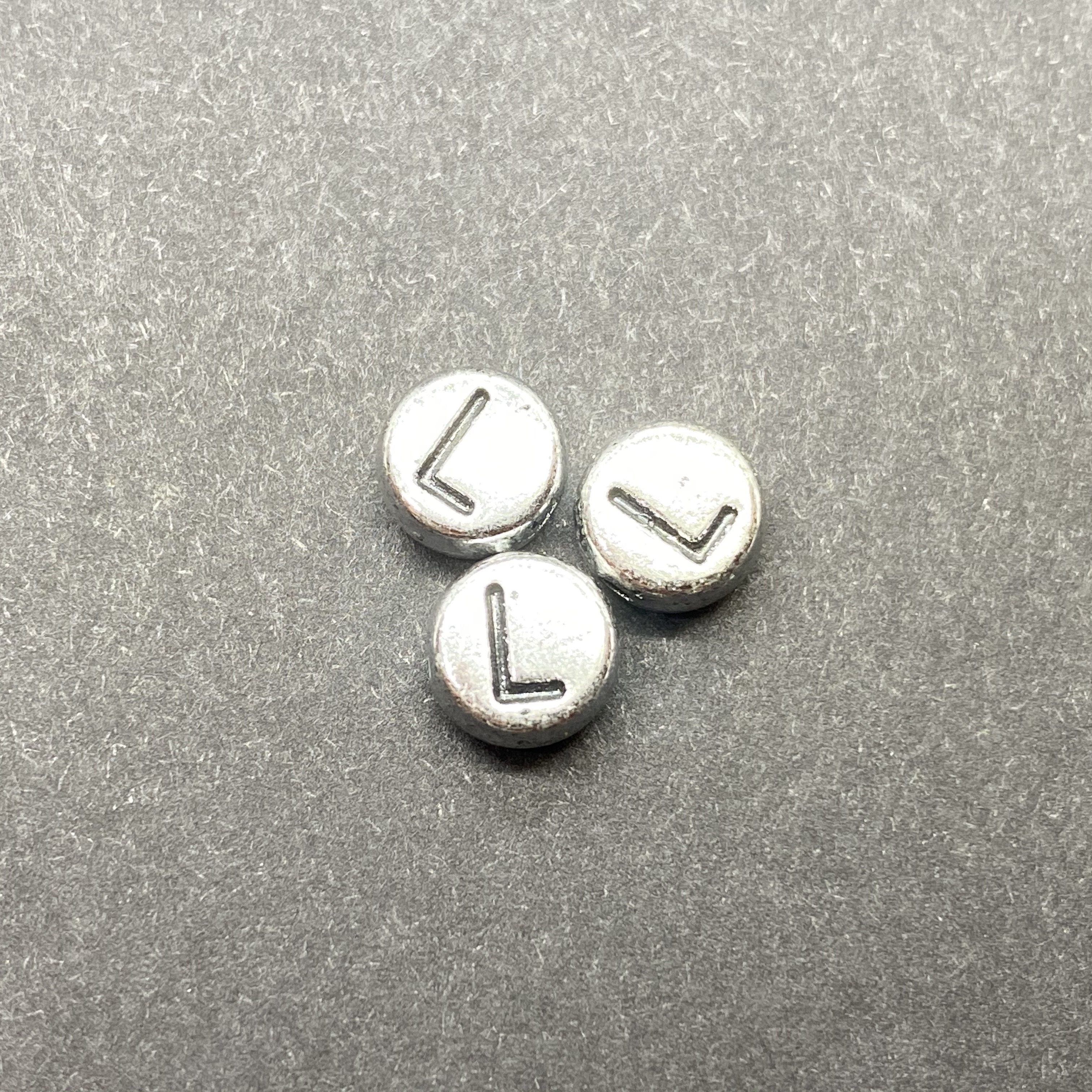 Műanyag ezüst színű kör l betűgyöngy (7mm)