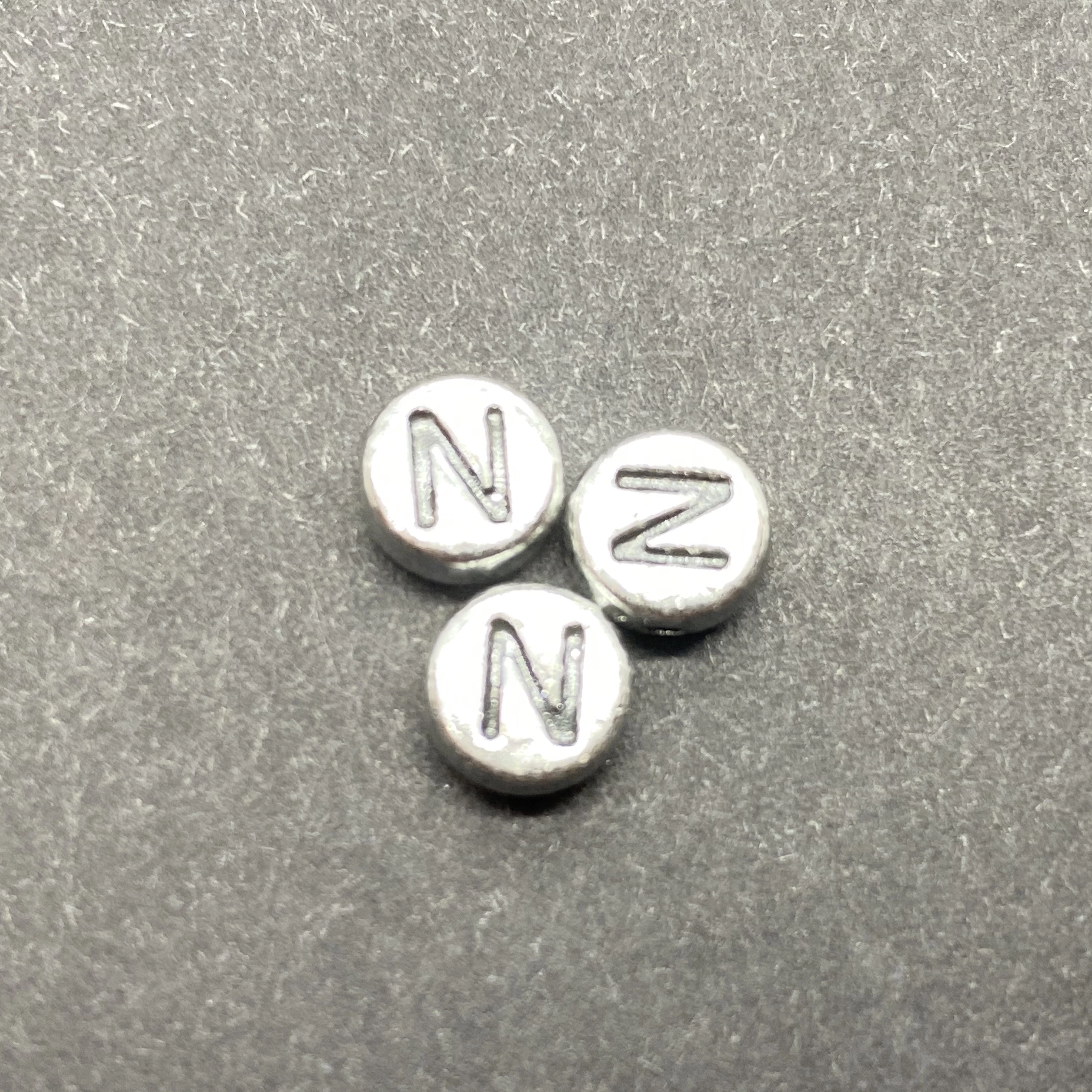 Műanyag ezüst színű kör n betűgyöngy (7mm)