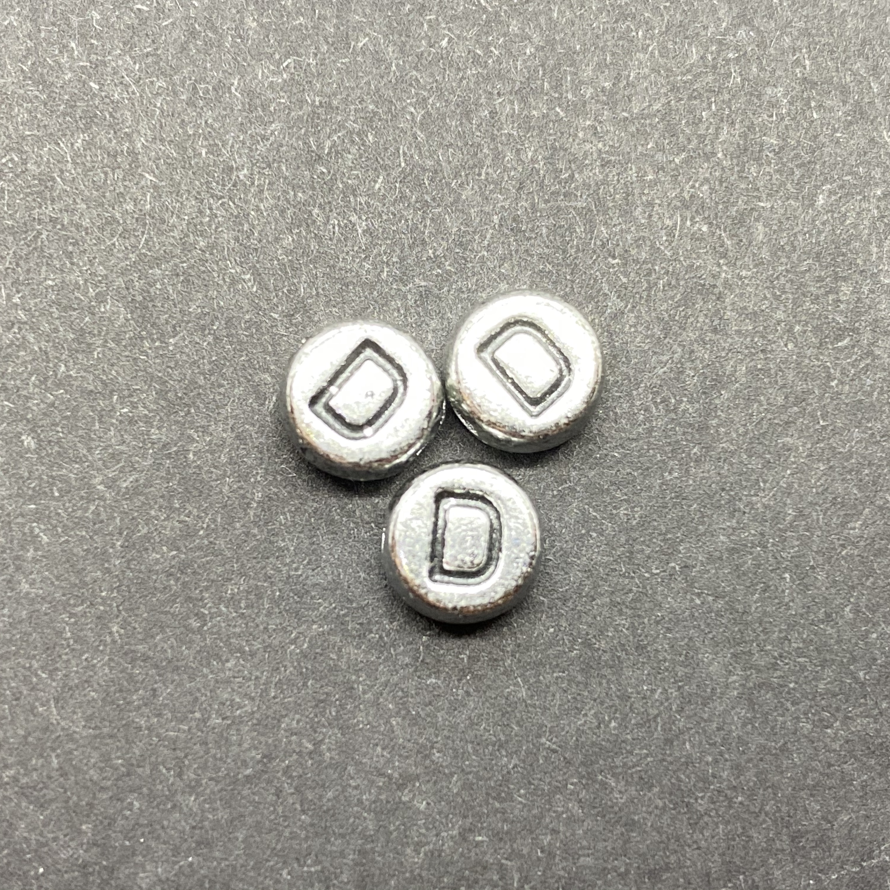 Műanyag ezüst színű kör d betűgyöngy (7mm)